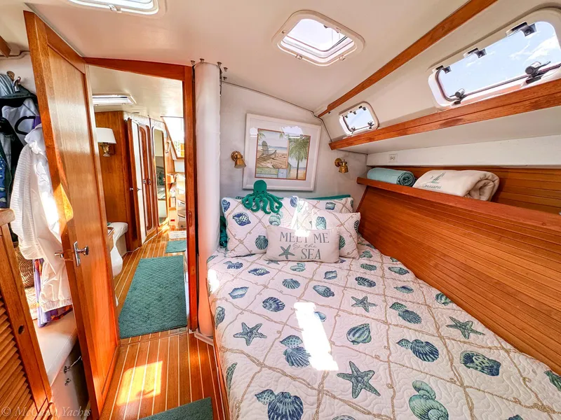 Slide: The Image of Cozy 1991 Catalina 42 yacht cabin with nautical-themed bedding and wooden interior. - 32