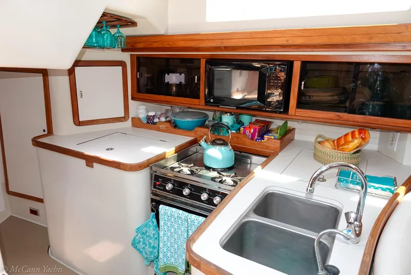 Slide: The Image of 1991 Catalina 42 yacht kitchen with stove, sink, and wooden cabinetry. - 43