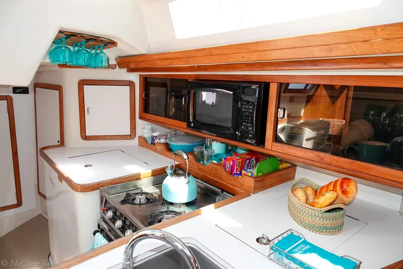Slide: The Image of Interior of 1991 Catalina 42 yacht kitchen with stove, microwave, and teal kettle. - 8