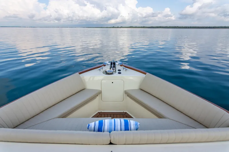 Slide: The Image of 2021 Palm Beach Motor Yachts PB65 bow with seating, on calm water under cloudy sky. - 12