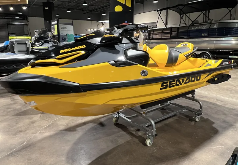 The Image of 2023 Sea-Doo RXT X 300 in showroom, yellow and black jet ski on display. - 1