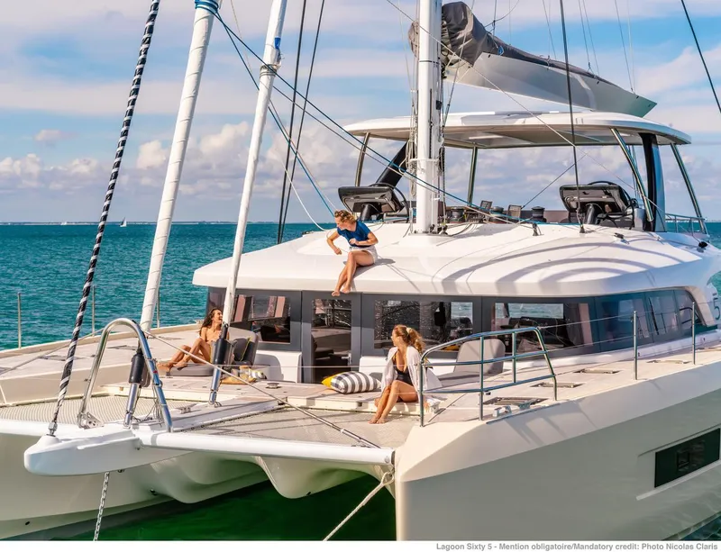 Slide: The Image of Luxurious 2025 Lagoon Sixty5 yacht with people relaxing on deck in sunny ocean setting. - 6