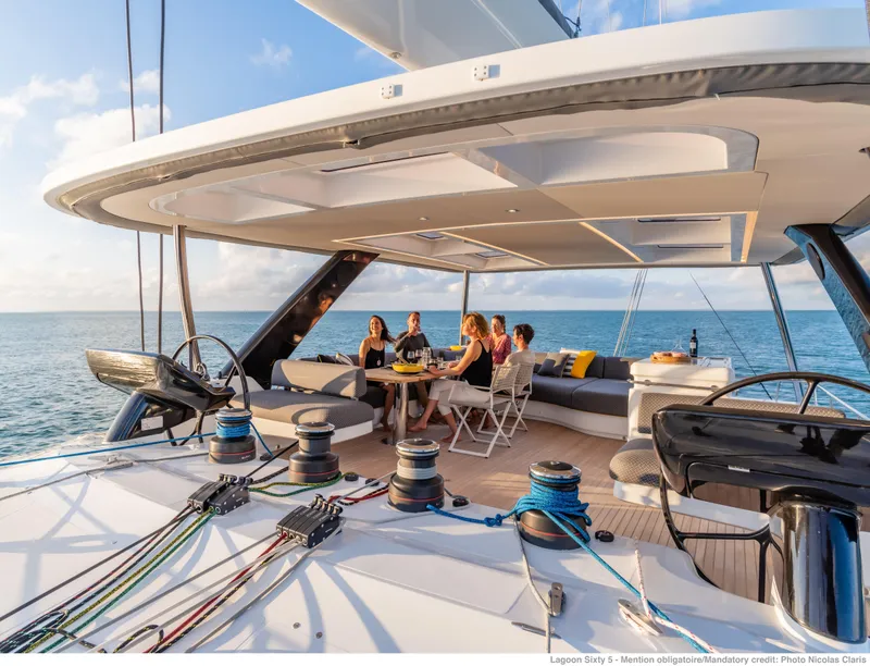 Slide: The Image of 2025 Lagoon Sixty5 yacht with people enjoying a meal on deck, ocean view. - 7
