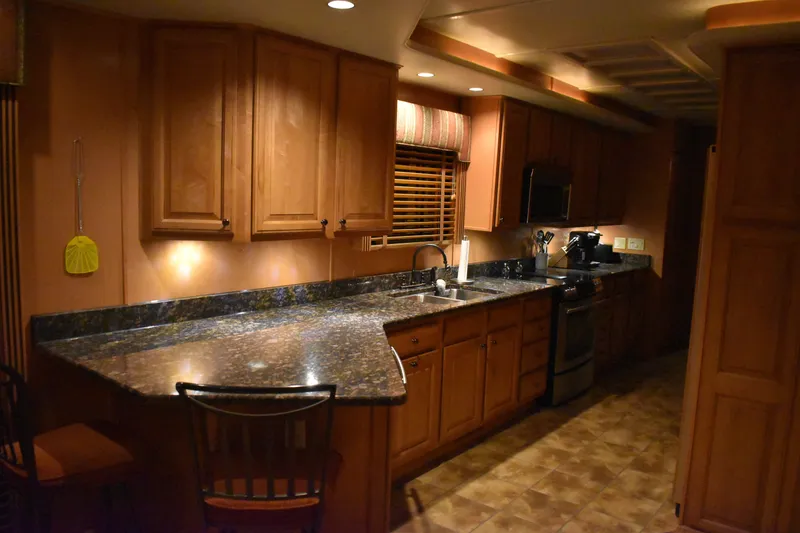 Slide: The Image of 2006 Sumerset Double Dippin houseboat kitchen with granite countertops and wooden cabinets. - 23