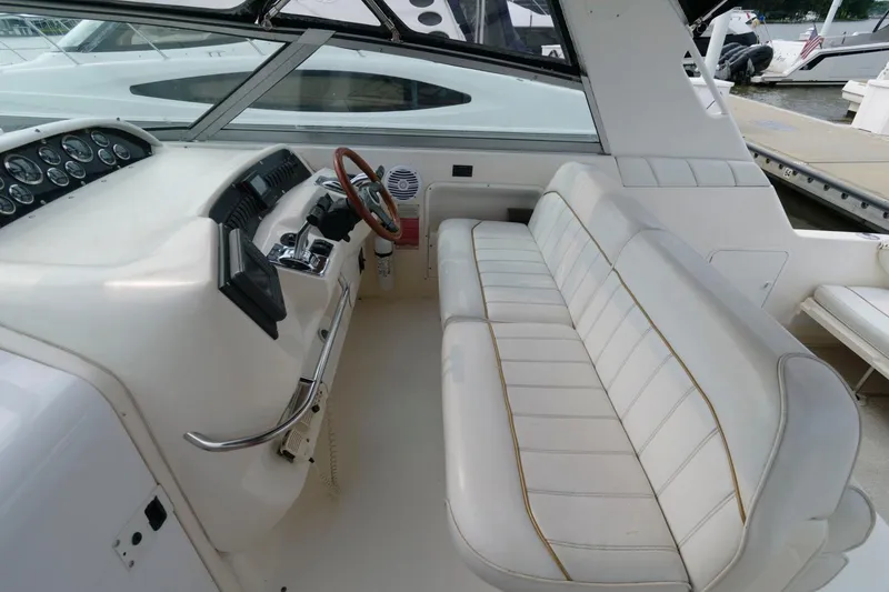 Slide: The Image of 1997 Sea Ray 330 Sundancer cockpit with white leather seating and wooden steering wheel. - 3