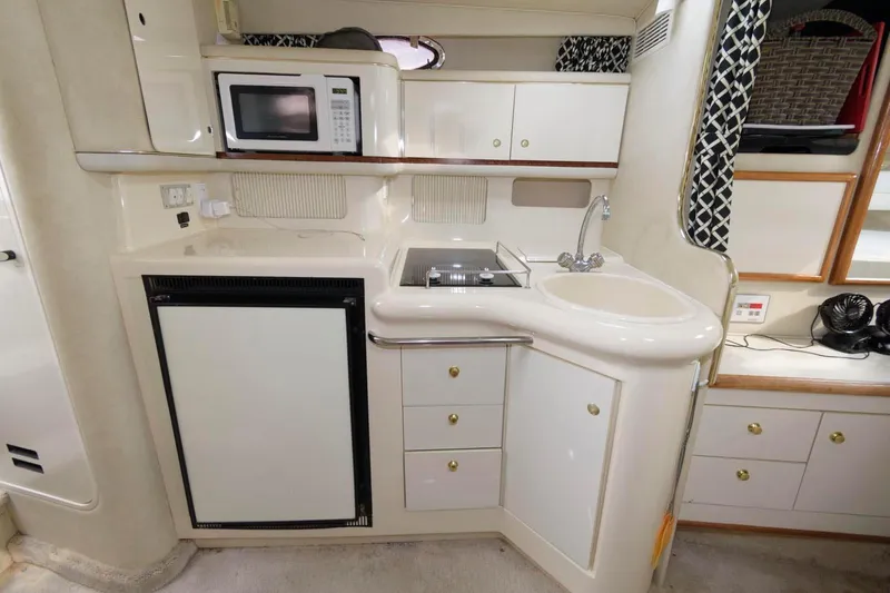 Slide: The Image of 1997 Sea Ray 330 Sundancer galley with microwave, sink, and storage cabinets. - 9
