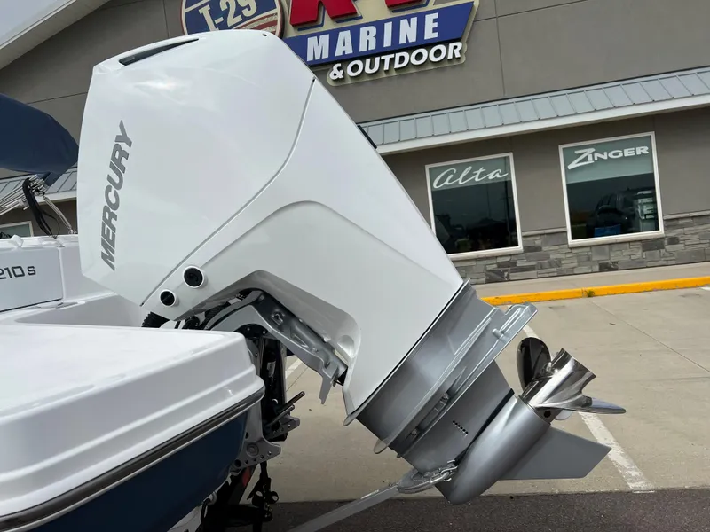 Slide: The Image of 2024 Tahoe 210 S boat with Mercury outboard motor at a marine dealership. - 14