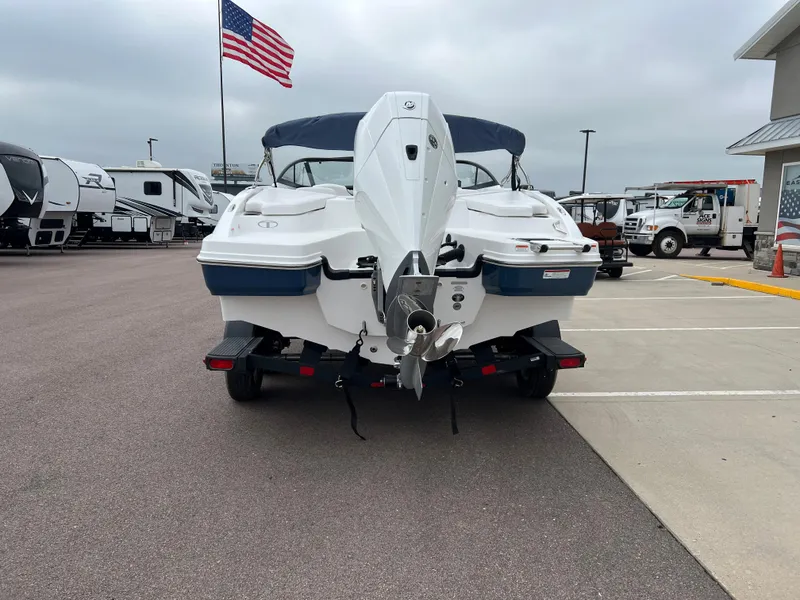 Slide: The Image of 2024 Tahoe 210 S boat rear view in dealership lot with American flag. - 2