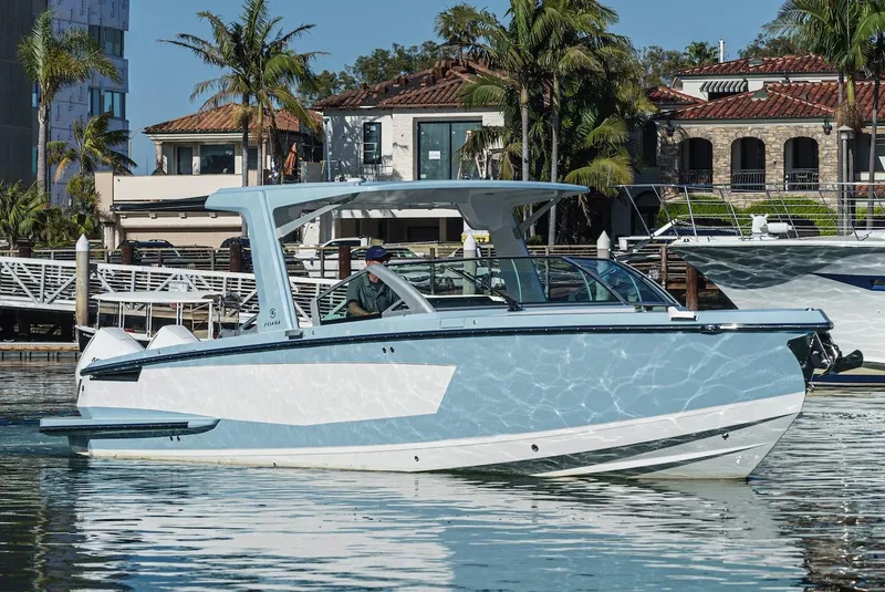 Slide: The Image of 2024 Aviara AV 32 boat docked in a marina with palm trees and buildings in the background. - 2