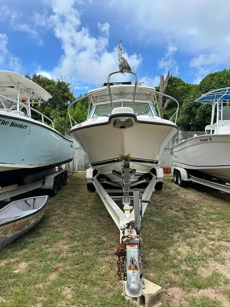 Slide: The Image of 2012 Pursuit 255 boat on trailer, surrounded by other boats, under a partly cloudy sky. - 11