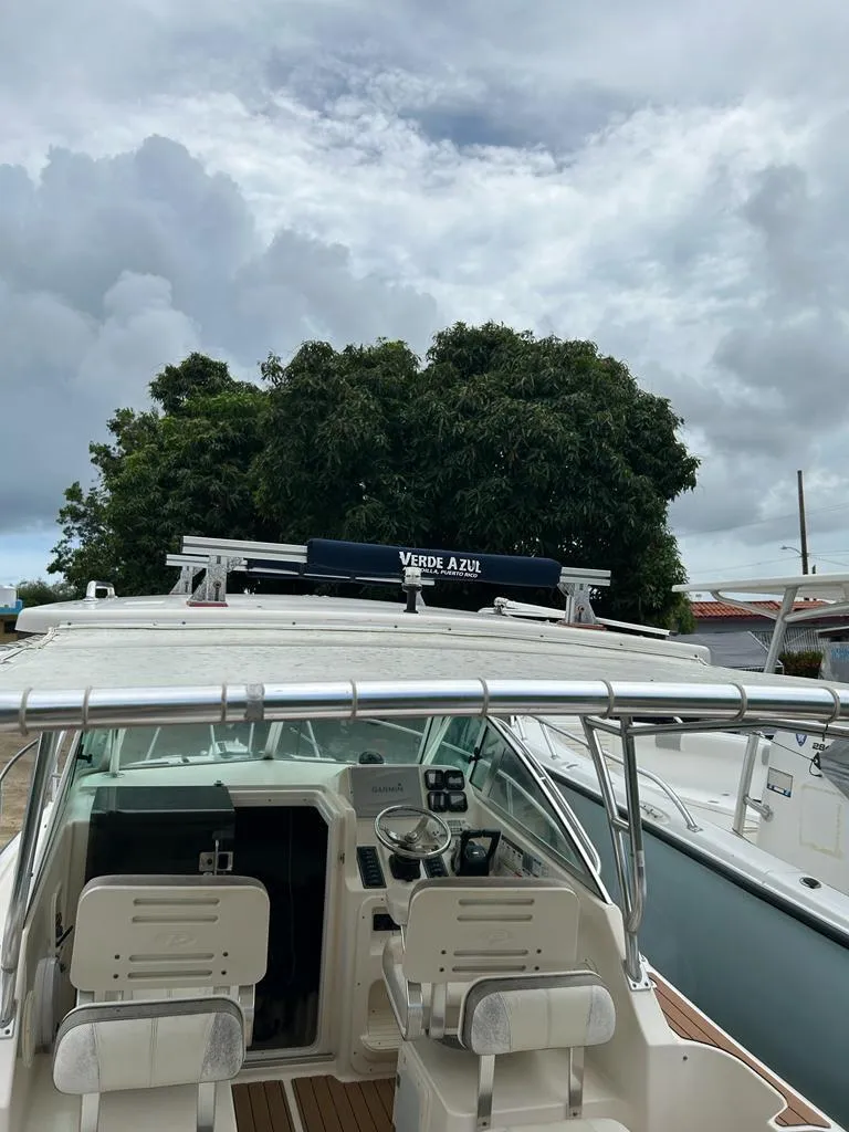 Slide: The Image of 2012 Pursuit 255 boat with dual seats, docked under cloudy skies. - 4