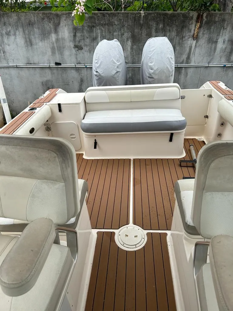 Slide: The Image of 2012 Pursuit 255 boat interior with cushioned seating and wooden deck. - 8