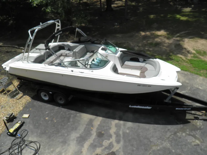 Slide: The Image of 2006 MasterCraft 280 SST boat on a trailer, parked on a driveway. - 2