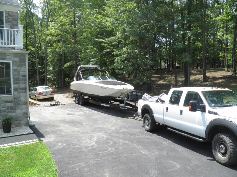 Slide: The Image of White 2006 MasterCraft 280 SST boat on trailer, towed by a white truck in a driveway. - 8