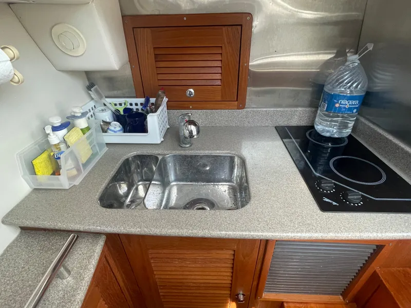 Slide: The Image of Compact kitchen area in a 2004 Glacier Bay Ocean Runner 3470 boat with sink and stove. - 34