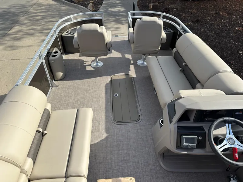 Slide: The Image of 2024 Sun Tracker Sportfish 24 XP3 pontoon boat interior with beige seating and steering console. - 5