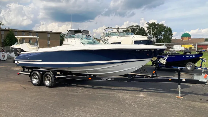 Slide: The Image of 2001 Chris-Craft Launch 25 boat on a trailer in a parking lot. - 0