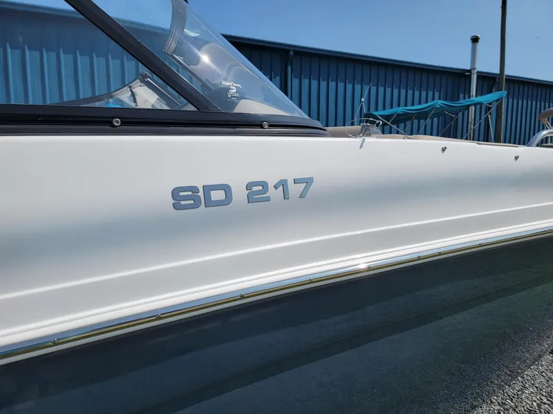 Slide: The Image of 2024 Hurricane SunDeck 217 OB boat side view with model number SD 217. - 30