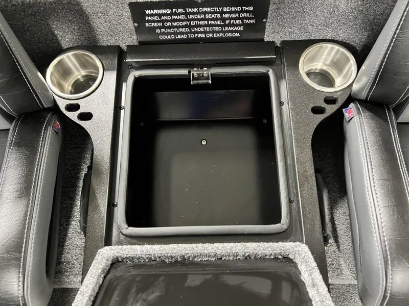 Slide: The Image of 2024 Phoenix 920 Elite boat interior storage compartment with cup holders and safety warning. - 20
