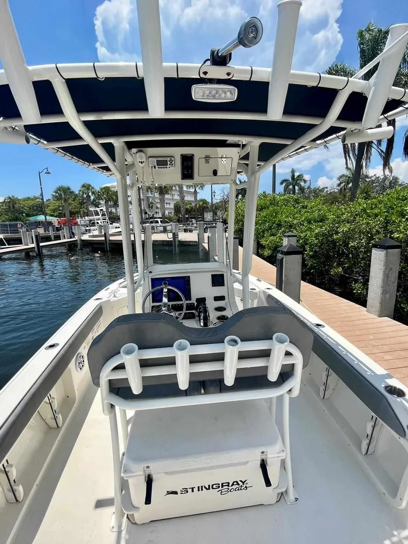 Slide: The Image of 2020 Stingray 216 CC boat docked at marina, featuring center console and rod holders. - 32