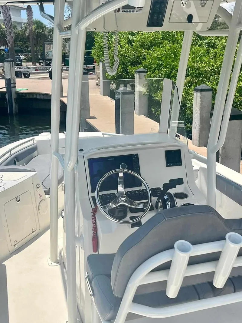 Slide: The Image of 2020 Stingray 216 CC boat cockpit with steering wheel and control panel at dock. - 4