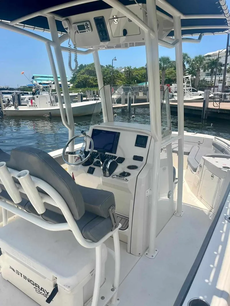 Slide: The Image of 2020 Stingray 216 CC boat at marina, featuring modern helm and seating. - 6