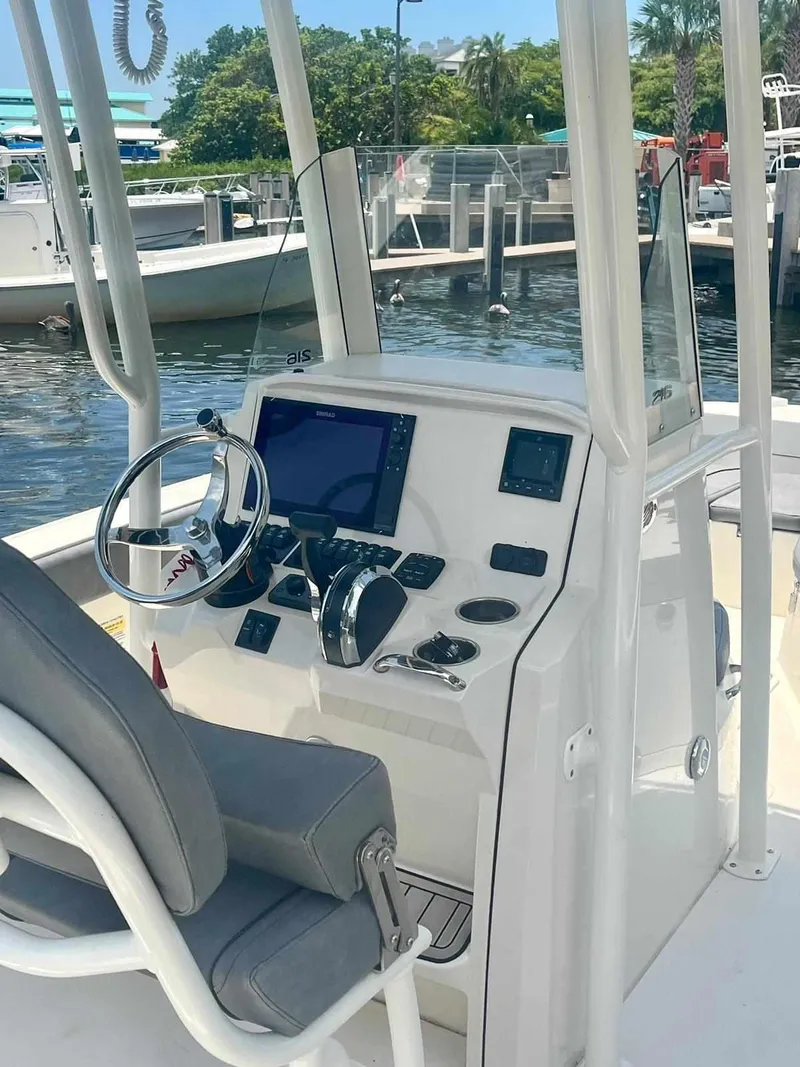 Slide: The Image of 2020 Stingray 216 CC boat console with steering wheel, navigation system, and controls at a marina. - 7