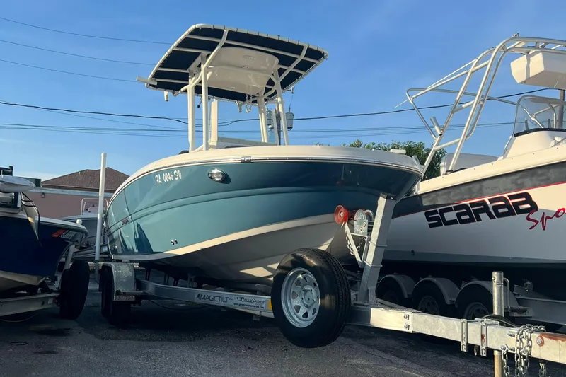Slide: The Image of 2020 Stingray 216 CC boat on a trailer, parked between other boats. - 8