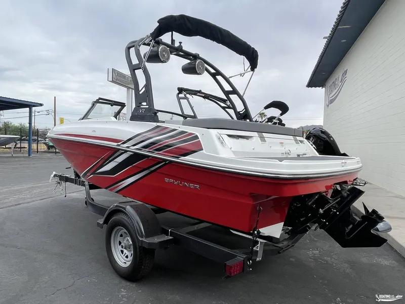 Slide: The Image of 2023 Bayliner VR4 boat in red and white on a trailer, parked outdoors. - 2