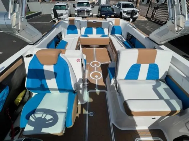Slide: The Image of 2022 MasterCraft X26 boat interior with blue and white seating, parked in a lot. - 20