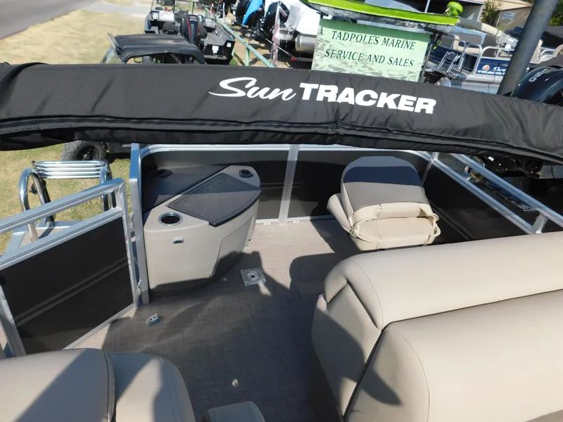 Slide: The Image of 2024 Sun Tracker Fishin' Barge 20 DLX pontoon boat interior with beige seating and black canopy. - 10