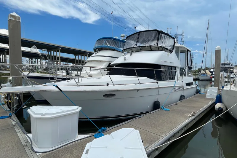 The Image of 1996 Carver 400 Cockpit Motor Yacht docked at marina under blue sky. - 0