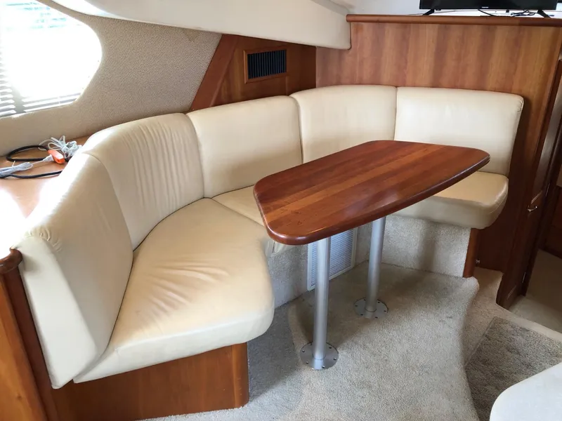 Slide: The Image of 2003 Silverton 35 Motor Yacht interior dining area with cream leather seating and wooden table. - 15