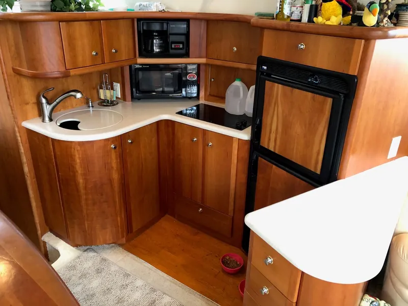Slide: The Image of 2003 Silverton 35 Motor Yacht kitchen with wooden cabinets, sink, microwave, and refrigerator. - 16