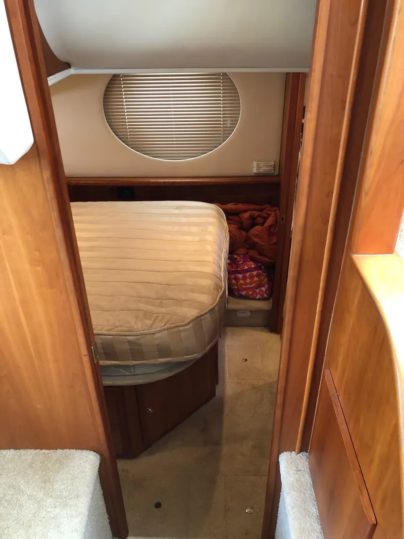 Slide: The Image of 2003 Silverton 35 Motor Yacht bedroom with circular window and wooden interior. - 24