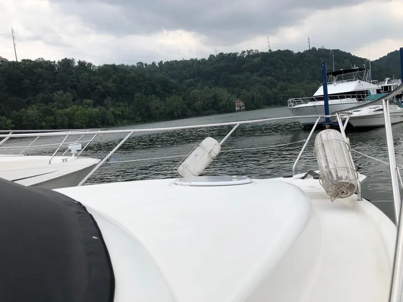 Slide: The Image of 2003 Silverton 35 Motor Yacht docked on a calm river with lush green hills. - 33