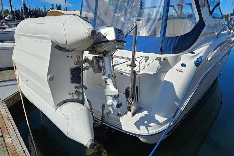 The Image of 2006 Bayliner 305 boat with attached inflatable dinghy and motor, docked at marina. - 0