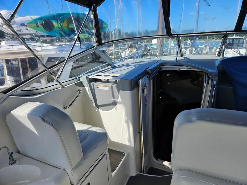 Slide: The Image of 2006 Bayliner 305 boat interior with seating and cabin entrance, docked at marina. - 11