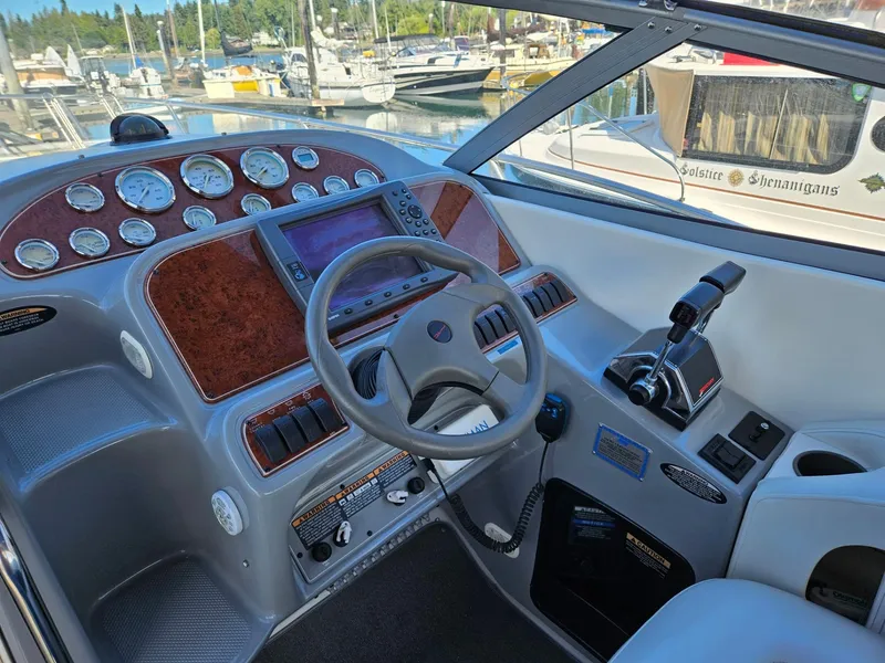 Slide: The Image of 2006 Bayliner 305 boat dashboard with steering wheel and control panel in a marina setting. - 12