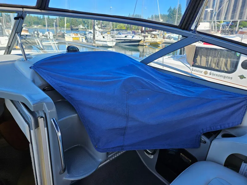 Slide: The Image of 2006 Bayliner 305 boat interior with blue cover, docked at marina. - 13