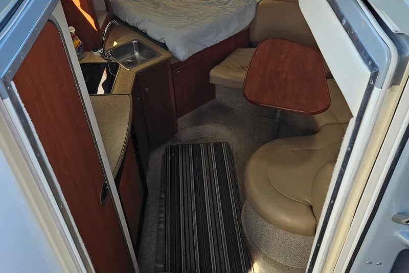 Slide: The Image of 2006 Bayliner 305 cabin interior with kitchenette, seating, and bed. - 2