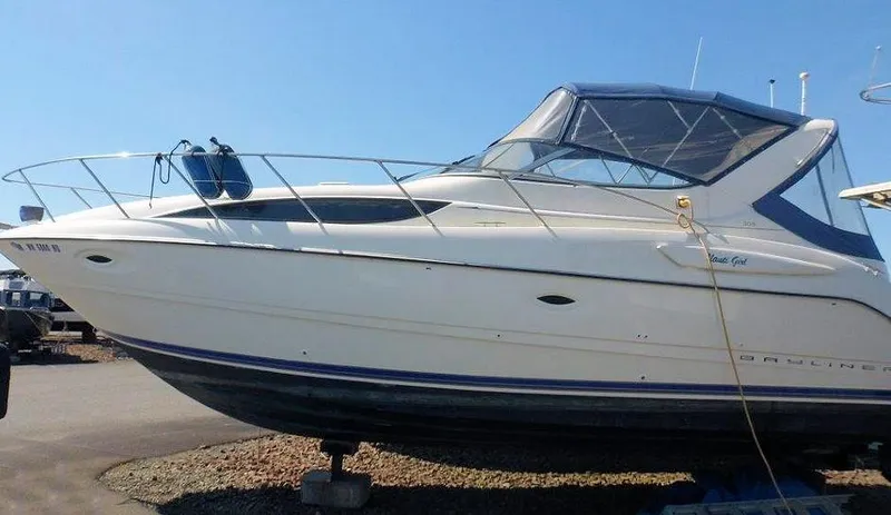 Slide: The Image of 2006 Bayliner 305 boat on dry dock, side view under clear blue sky. - 23