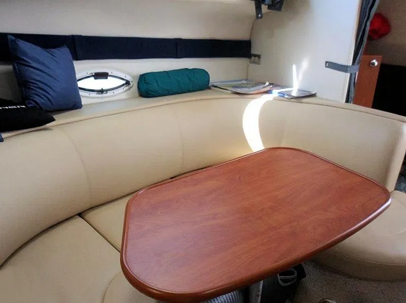 Slide: The Image of Interior of 2006 Bayliner 305 boat with beige seating and wooden table. - 3