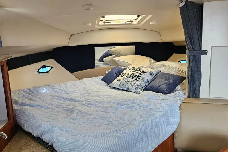 Slide: The Image of 2006 Bayliner 305 cabin interior with cozy bed and nautical-themed pillows. - 5