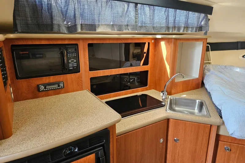 Slide: The Image of 2006 Bayliner 305 interior kitchen with microwave, sink, and stove. - 6