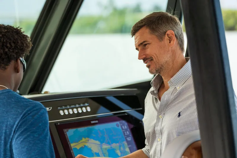 Slide: The Image of Two people discussing navigation on a 2024 Boston Whaler 360 Outrage boat. - 15