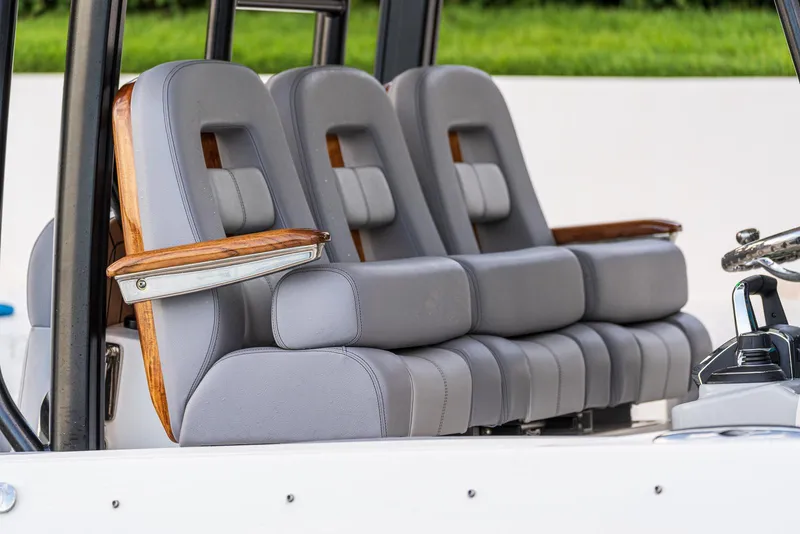 Slide: The Image of 2024 Boston Whaler 360 Outrage interior seating with gray upholstery and wooden armrests. - 4