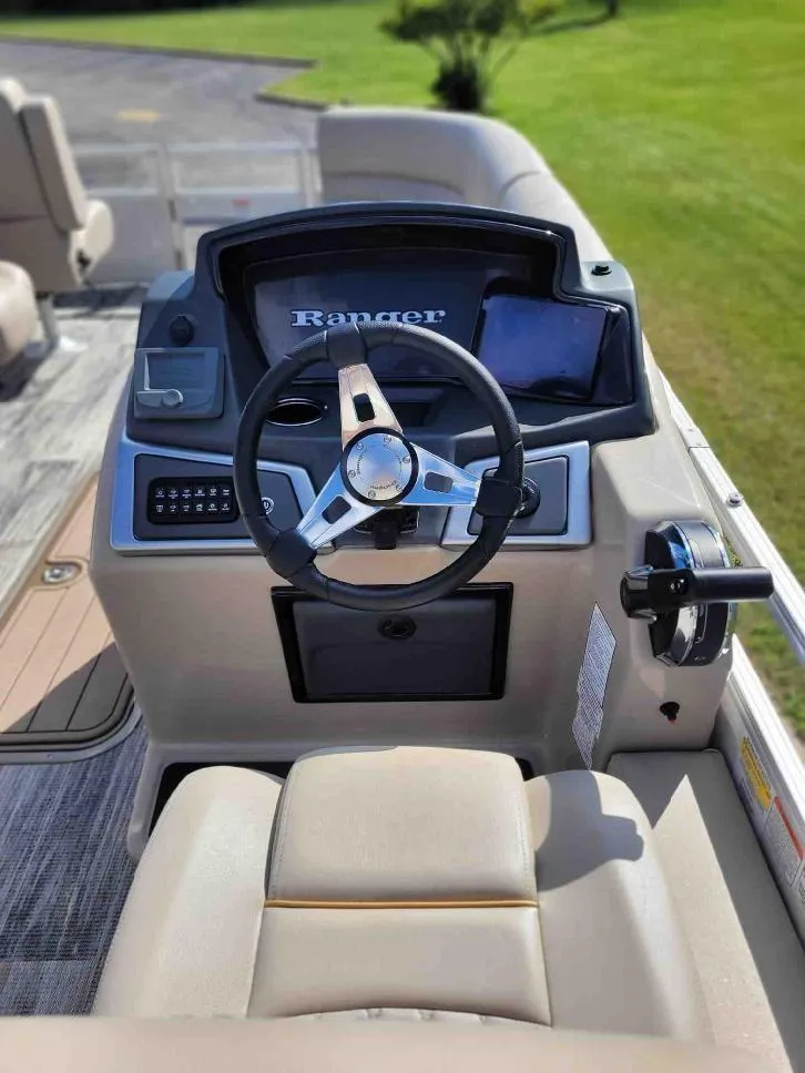 Slide: The Image of 2024 Ranger Reata 223FC boat helm with steering wheel and control panel. - 2