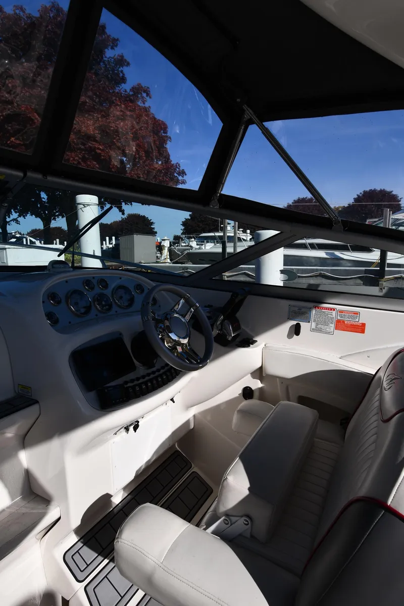 Slide: The Image of 2006 Monterey 298SC Super Sport boat interior with seating and steering wheel, docked by water. - 12