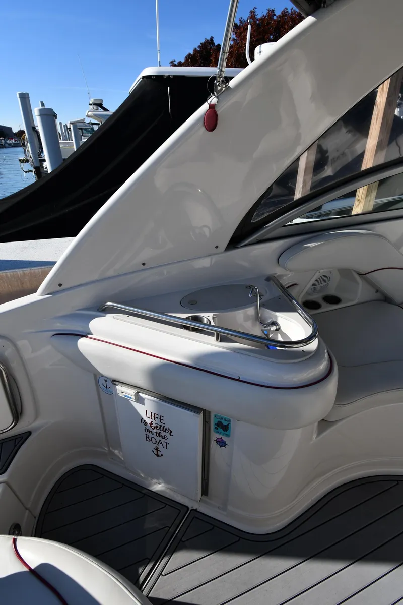 Slide: The Image of 2006 Monterey 298SC Super Sport boat interior with seating and table, docked under clear blue sky. - 29